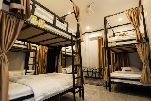 a room with three bunk beds with white sheets at Nam Phou Hostel in Thakhek