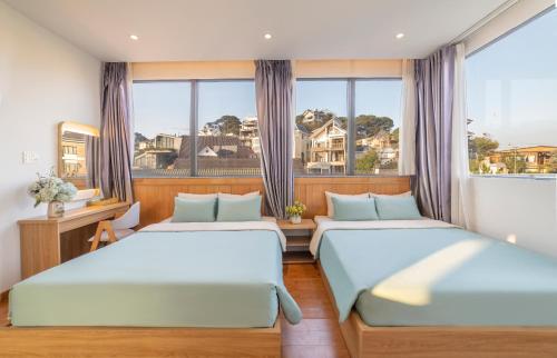 two beds in a room with a window at Dalat Hotel & Villa by Pham Gia in Xuan An