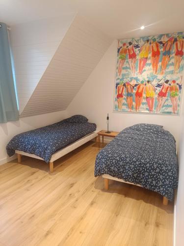 a bedroom with two beds and a painting on the wall at Maison des bois in Neufchâtel-Hardelot