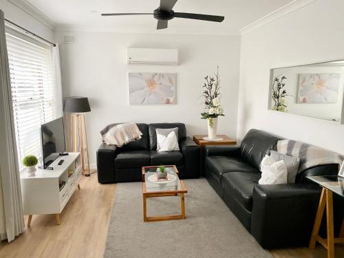 a living room with a black couch and a table at Annie's Apartment in Mount Gambier