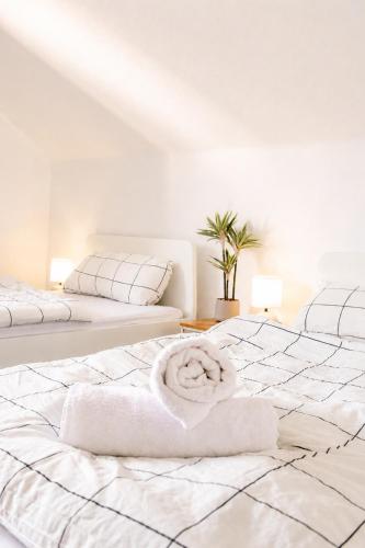 a white bedroom with two beds with towels on them at Helle Ferienwohnung im Schwarzwald - 2 Schlafzimmer - WLAN - Holzapfel Apartments in Villingen-Schwenningen