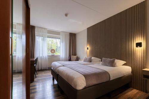 a hotel room with a large bed and a window at 50|50 Hotel Belmont in Ede