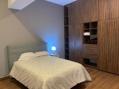 a bedroom with a bed and a wooden cabinet at Departamento Torre el Morado MAS EXPERIENCIA A CABALLO in La Concepción
