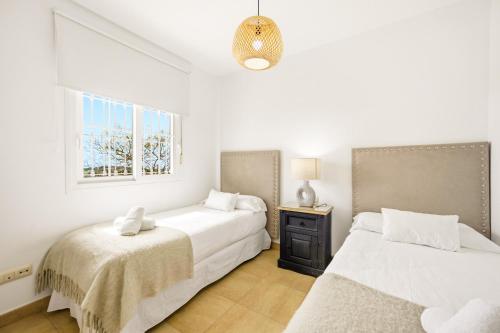 two beds in a white room with a window at Costa Africana in Vejer de la Frontera