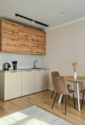 a kitchen with white cabinets and a table with chairs at Жк "AUEZOV" in Kokshetau