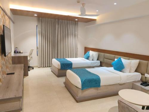 a hotel room with two beds and a desk at CENTRAL A BOUTIQUE HOTEL in Belgaum