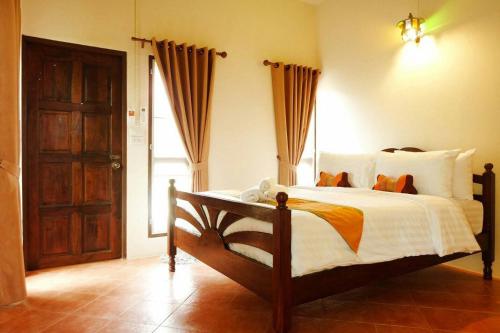a bedroom with a bed and a wooden door at Baan Buapatumma in Mae Sai