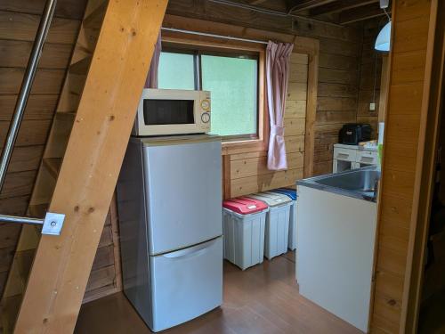 a kitchen with a microwave on top of a refrigerator at のんびれっじ つくし棟 in Anazawa