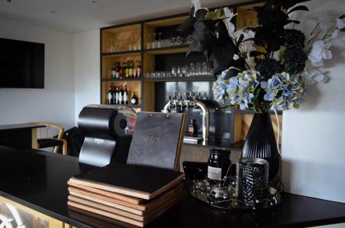a bar with a vase of flowers and books at The Ridge Guesthouse in Richards Bay