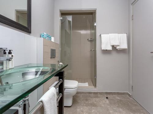 a bathroom with a sink and a toilet and a shower at Infinity Self Catering Apartments in Bloubergstrand