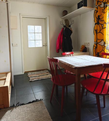 a dining room with a table and red chairs at Päivärannantila in Pihtipudas
