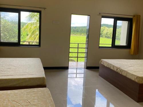 two beds in a room with two windows at Hiran Holidays in Sasan Gir