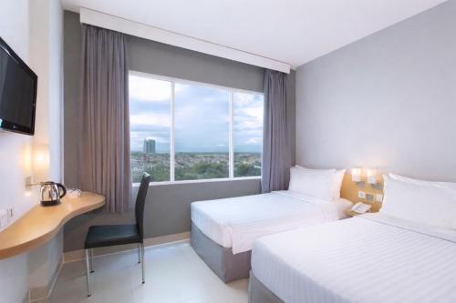 a hotel room with two beds and a desk and a window at favehotel Solo Baru in Solo