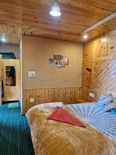 a bedroom with a large bed and wooden walls at Ananta Valley Home's in Kulu