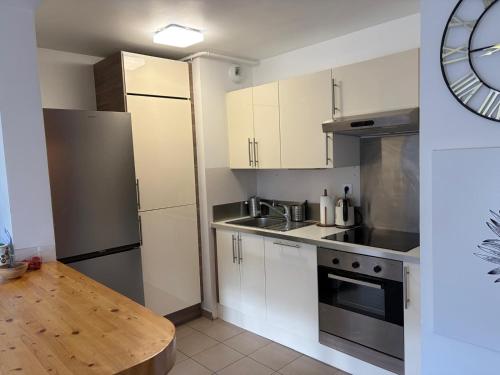 a kitchen with white cabinets and a stainless steel refrigerator at Appartement Belle Vue in Gréoux-les-Bains