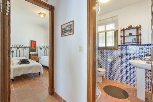 a bathroom with a sink and a toilet and a bed at Villa Quietud in Salobreña