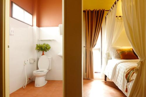 a bathroom with a bed and a toilet in a room at Baan Buapatumma in Mae Sai