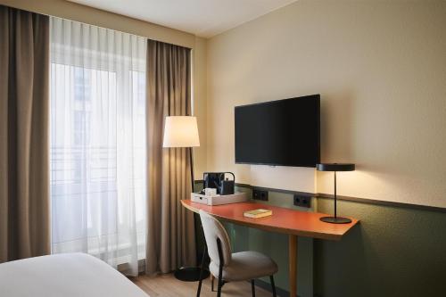 a hotel room with a desk with a television and a bed at iStay by NH Berlin City Ost Hotel in Berlin