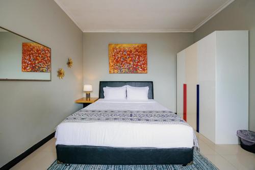 a bedroom with a large bed and two paintings on the wall at The Lavana Signature Villa Alessa Puncak in Puncak