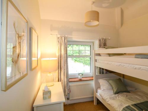 a bedroom with two bunk beds and a window at Lumford Mill Cottage in Bakewell