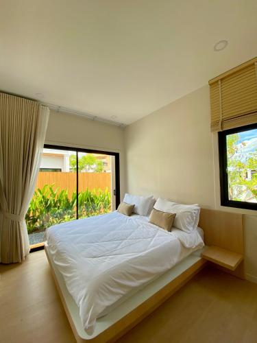a bedroom with a large white bed with a window at The Town Pool Villas in Krabi