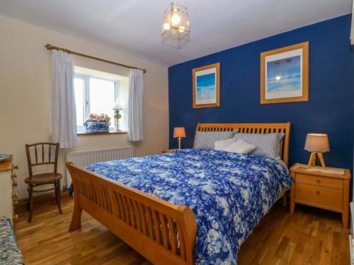 a bedroom with a bed with a blue wall at Pen Glorian in Conwy
