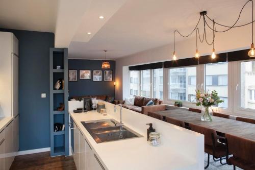 a kitchen and living room with a sink and a couch at Stylish Central Flat, Steps to Beach in Ostend