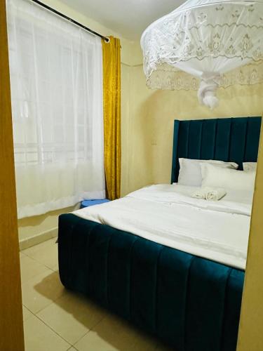 a bed with a blue headboard in a room with a window at ONE BEDROOM THIKA ROAD ,TRM DRIVE Homes by Essyruby in Nairobi