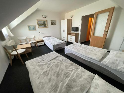 a bedroom with two beds and a table and chairs at Penzion U Kašných in Mníšek pod Brdy