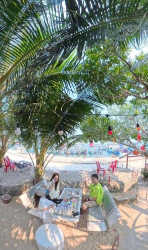 a group of people sitting under a palm tree on the beach at Hoa Bien Motel in Ly Son