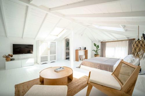 a white bedroom with a bed and a table at Kurabiye Hotel in Alaçatı