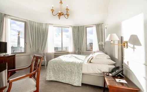 a bedroom with a bed and a desk with a telephone at Grand Hotel Cravat in Luxembourg