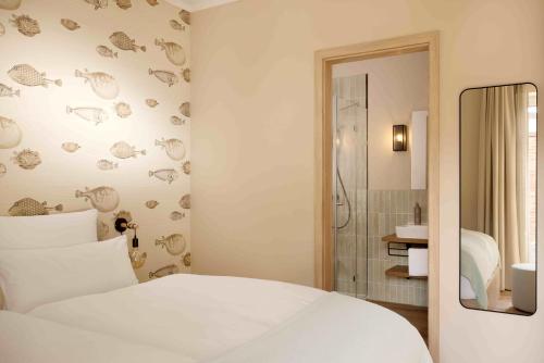 a bedroom with a white bed and a shower at Gezeiten Suites Büsum - Neueröffnung in Büsum