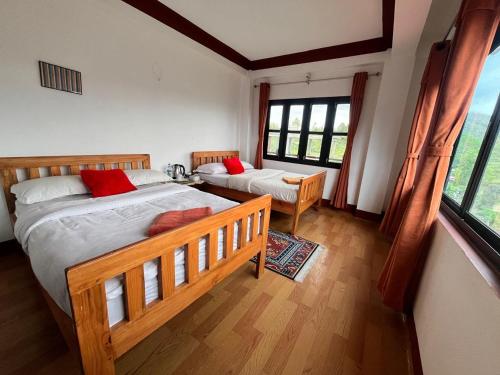 a bedroom with two beds and a large window at Hotel PeaceFul in Bandipur
