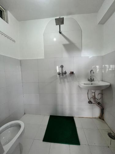 a white bathroom with a sink and a toilet at Hotel PeaceFul in Bandipur