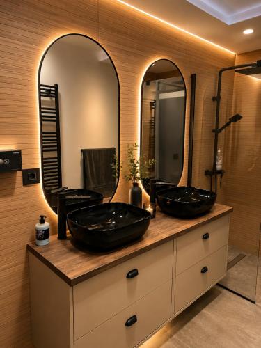 two sinks on a counter in a bathroom with two mirrors at Da Vinci Luxury Home Otopeni in Otopeni