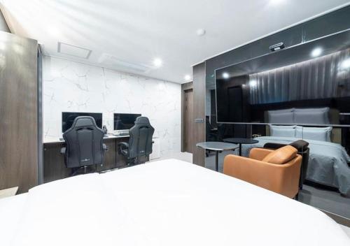 ein Zimmer mit zwei Schreibtischen und Stühlen sowie einem Bett in der Unterkunft Rosy Hotel in Cheongju