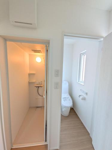 a white bathroom with a toilet and a sink at cottage hapo in Higashikagura
