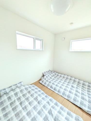 two beds in a room with two windows at cottage hapo in Higashikagura