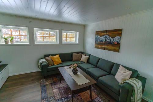 a living room with a green couch and a table at Sigridhuset in Moskenes