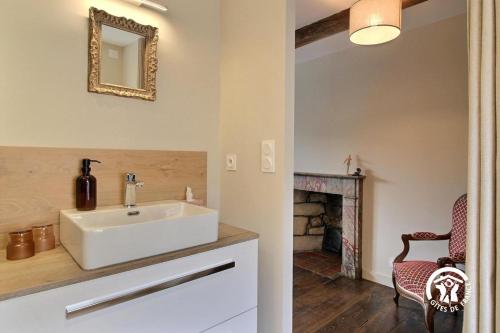 a bathroom with a white sink and a fireplace at Le clos des sittelles in Theix