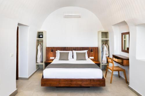 a bedroom with a bed and a table and a chair at Santorini Rooftop Hot Tub Suite with Panoramic Views in Akrotiri