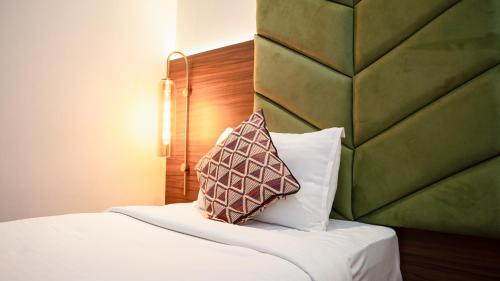a bed with a headboard and a pillow on it at Hotel Heritage Grand in Thane