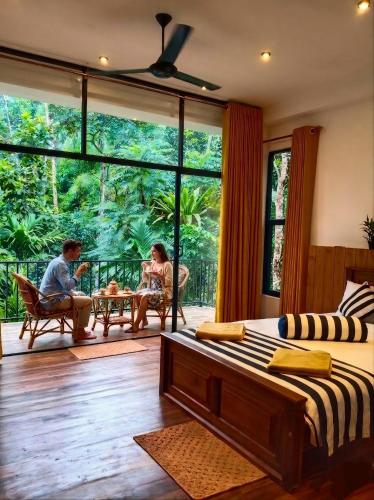 a bedroom with two people sitting on a porch at Ella Green Cottages in Ella