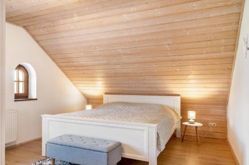 a bedroom with a white bed and a wooden ceiling at Fewo Enzian in Breitenberg