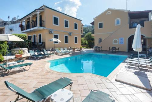 a swimming pool with lounge chairs and a building at Ariti Apartments in Kassiopi