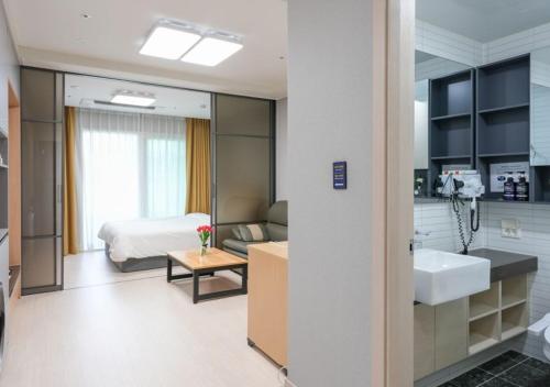 a bathroom with a sink and a bedroom with a bed at Firstcity Hotel YEOSU in Yeosu