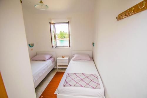 a small room with two beds and a window at Apartments Punta Blue & Orange 5 m from the sea in Punta Križa