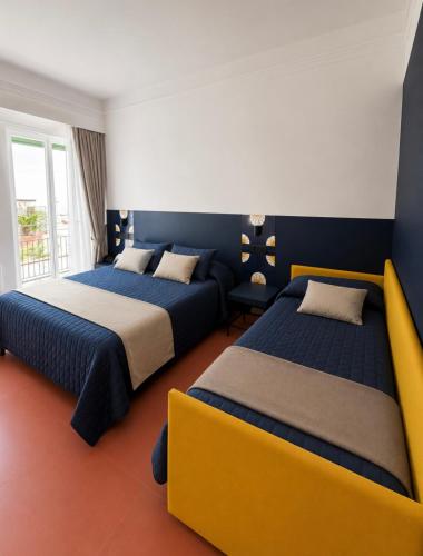 two beds in a room with blue and yellow at Hotel Sole in Maiori