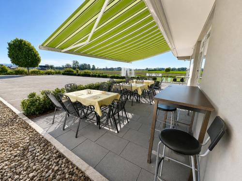 eine Terrasse mit Tischen, Stühlen und einem Sonnenschirm in der Unterkunft Hotel B3 GmbH in Mauthausen